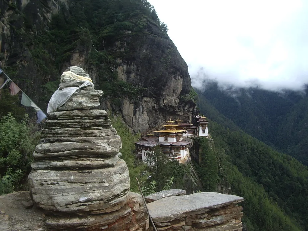 A stacked stone cairn on a cliff path facing the Tiger's Nest monastery above Paro valley